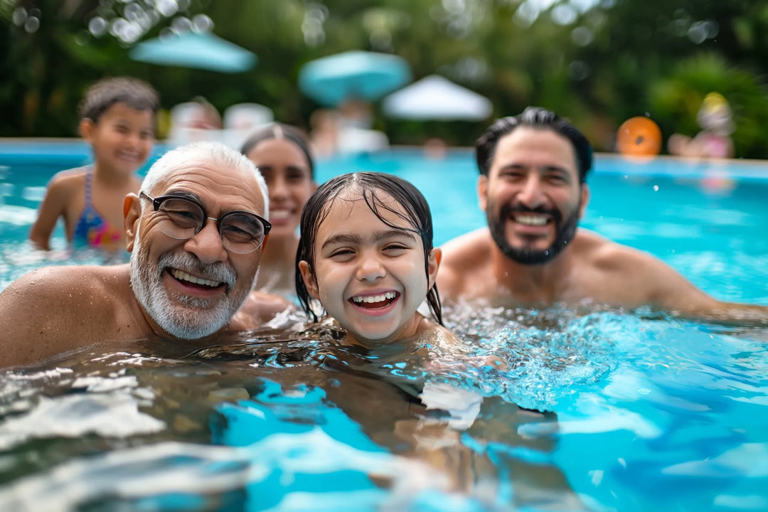 Family enjoying time in a pool with a young girl smiling at the camera.